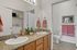 Bright bathroom featuring dual sinks with elegant granite countertops, modern decor, and convenient in-unit laundry access.