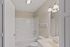 Bright, inviting bathroom with an elegant white tile bathtub, sleek vanity, and contemporary light fixtures.