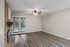 Charming living room with modern wood floor, stone fireplace, and bright double doors opening to a serene garden view.