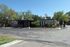 Charming single-story building with modern design, lush greenery, and ample parking under a clear blue sky.