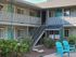 Charming apartment exterior with turquoise doors and relaxing patio chairs set amidst lush greenery.