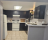Modern kitchen with sleek dark cabinets, white appliances, and a cozy breakfast bar, designed for both style and functionality.