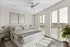 Sunlit bedroom with modern decor, featuring a plush bed, elegant nightstands, and large windows with blinds allowing natural light to flood the space.