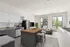 Modern open-concept kitchen and living area with sleek cabinets, stylish island, and large windows offering abundant natural light.