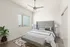 Chic bedroom featuring a modern gray bed, elegant bedside lamps, and a stylish bench, complemented by natural light through large windows.