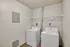 Modern laundry room featuring sleek white washer and dryer with ample shelving in a cozy, well-lit space.