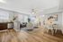 Bright, open-concept living space with stylish wooden flooring, modern kitchen, and cozy sitting area, perfect for relaxation.