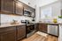 Modern kitchen with dark wood cabinets, granite countertops, stainless steel appliances, and natural light streaming through a large window.