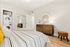 Bright and cozy bedroom with elegant striped bedding, mirrored dresser, and convenient in-unit washer-dryer.