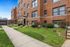 Charming brick apartment building with manicured greenery and welcoming pathways.