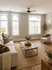 Inviting living room with natural light, featuring a cozy sofa, stylish armchair, and elegant decor on hardwood floors.
