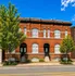 Charming brick apartment building with arched windows and inviting entrances, flanked by lush greenery.