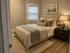 Cozy bedroom featuring a plush bed with elegant textiles, soft lighting from a modern lamp, and a serene artwork above the headboard.