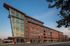 Contemporary apartment building with striking modern architecture, featuring large glass windows and brick accents on a clear day.