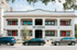 Charming two-story building with red doors, known as The Studios at Maverick Park, exuding modern appeal and urban convenience.