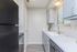 Modern kitchen with sleek black appliances, white countertops, and stylish cabinetry, well-lit by natural sunlight.