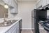 Modern kitchen with sleek black appliances, elegant light fixtures, and chic countertops in a cozy layout.