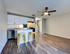 Modern open-concept kitchen with sleek countertops, bright cabinetry, and stylish barstools, featuring elegant lighting and chic wood flooring.