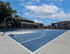 Vibrant outdoor basketball court surrounded by modern apartment buildings under a bright blue sky.