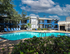 Inviting apartment complex with a sparkling pool, surrounded by lush greenery and stylish blue accents, offering a serene and luxurious living experience.