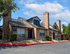 Charming brick apartment complex with cozy chimneys and beautiful landscaping under a bright blue sky.