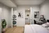 Modern bedroom with a cozy workspace, featuring a stylish desk and chair, alongside a convenient in-unit washer and dryer. Highlighted by elegant artwork and natural lighting.