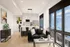 Modern open-plan living area with a sleek kitchen, sunlight streaming through large windows, and stylish decor.