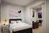 Cozy apartment bedroom with sleek black bed frame, modern artwork, and adjoining living area featuring a stylish TV setup.