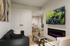 Modern living room with chic d&eacute;cor, featuring a sleek black sofa, stylish artwork, wall-mounted TV, and a cozy electric fireplace. Open layout leads to a tasteful dining area.