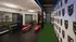 Contemporary fitness room with state-of-the-art equipment, sleek red benches, mirrored walls, and vibrant green turf, creating an energizing workout environment.