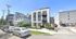 Contemporary three-story apartment building with sleek design, featuring large windows and modern landscaping on a vibrant city street.