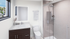 Elegant bathroom featuring a modern glass shower, stylish vanity with a marble countertop, and a scenic window view.