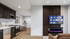 Modern open-plan living room featuring a sleek kitchen, stylish entertainment center with a flat-screen TV, and a contemporary fireplace.