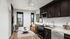 Modern apartment interior with sleek kitchen, cozy living area, and large windows offering a cityscape view.