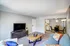 Inviting living room with cozy seating, modern TV setup, and a glimpse into a chic dining area and contemporary kitchen.