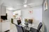 Charming dining area with sleek glass table, modern kitchen featuring white cabinetry and stylish decor.