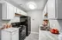 Modern kitchen with sleek white cabinets, black appliances, and elegant marble countertops.