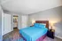 Inviting bedroom with plush blue bedding, elegant hardwood floors, and en-suite bathroom, offering a cozy retreat.