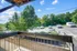 Charming balcony view overlooking a scenic parking area surrounded by lush greenery and a bright blue sky.