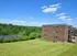 Inviting residential building with brick exterior, surrounded by lush greenery and open sky.