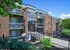 Charming brick apartment complex with private balconies, surrounded by lush greenery, showcasing modern design and accessibility.