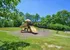 Inviting playground with colorful slides and swings, surrounded by lush greenery under a clear blue sky.