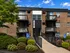 Charming brick apartment building with lush landscaping and accessible entrance in a serene setting.