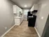 Modern galley kitchen with sleek black appliances, elegant white cabinetry, and chic wooden flooring.