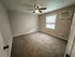 Inviting bedroom space with modern ceiling fan, neutral walls, and air conditioning, perfect for personalization.