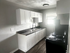 Chic modern kitchen with sleek white cabinetry, dark countertops, and natural light creating a welcoming atmosphere.