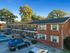 Charming two-story brick apartment complex with ample parking and lush greenery, ideal for comfortable living.