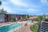 Inviting apartment complex showcasing a sparkling pool, cozy seating area, and well-maintained landscaping under a bright blue sky.
