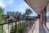 Inviting apartment complex featuring a sunlit balcony with views of a lush garden and shared outdoor pool area.