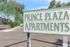 Charming entry sign for Prince Plaza Apartments, set amidst lush greenery and a spacious parking area.